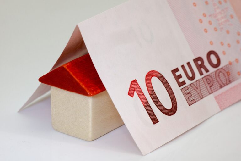 Ein 10 Euro Schein, der über einem Haus-Symbol liegt